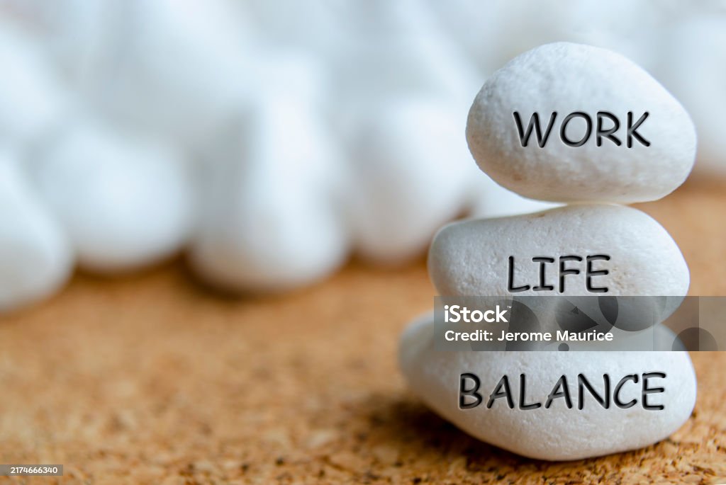 tiga buah batu berwarna putih ditumpuk ke atas, masing-masing batu ada tulisan work, life, balance.